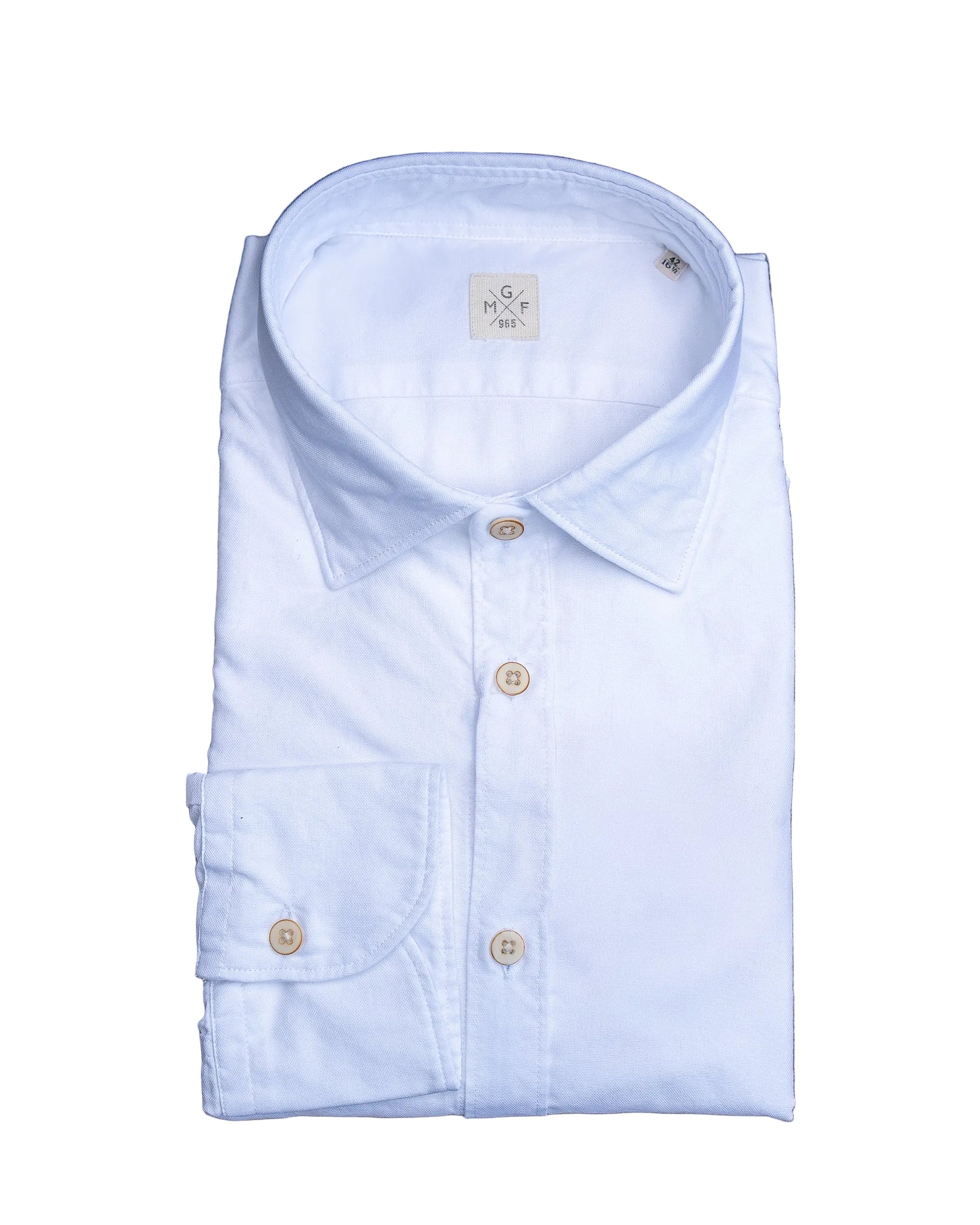 Folded white washed oxford cloth shirt with gold buttons on a stone surface