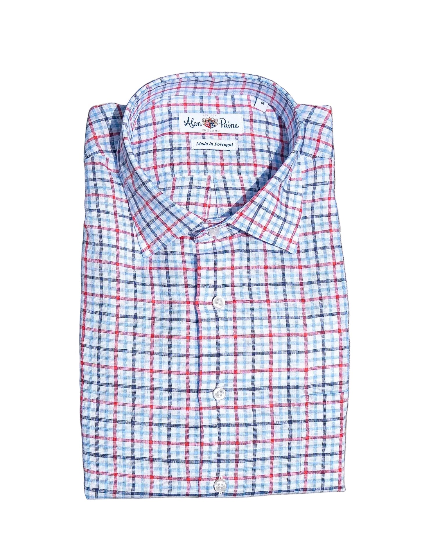 Folded plaid red white and blue shirt with a brand label on a stone surface